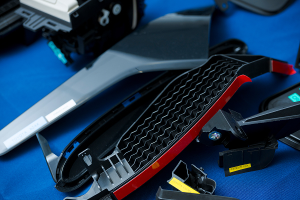 写真：樹脂製品の一例その1。黒色のパーツが青い布の上に並べられている。