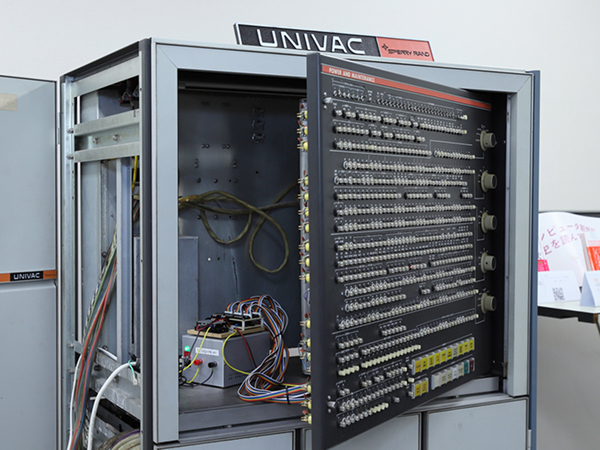 写真：扉を開いたユニバックの大型コンピュータ筐体内部。配線や制御パネルが見える。