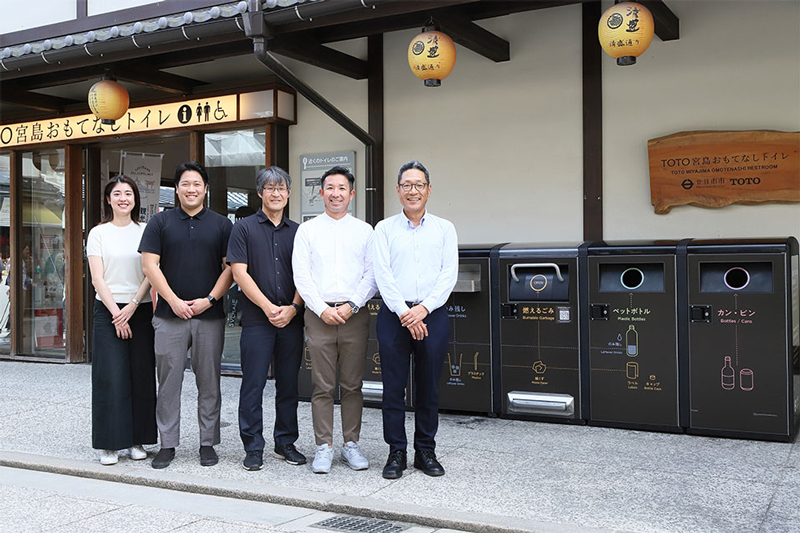 写真：宮島おもてなしトイレ前に並ぶ一同。左から栗原、池田、中島氏、児玉氏、廣本氏の順に並んでいる。